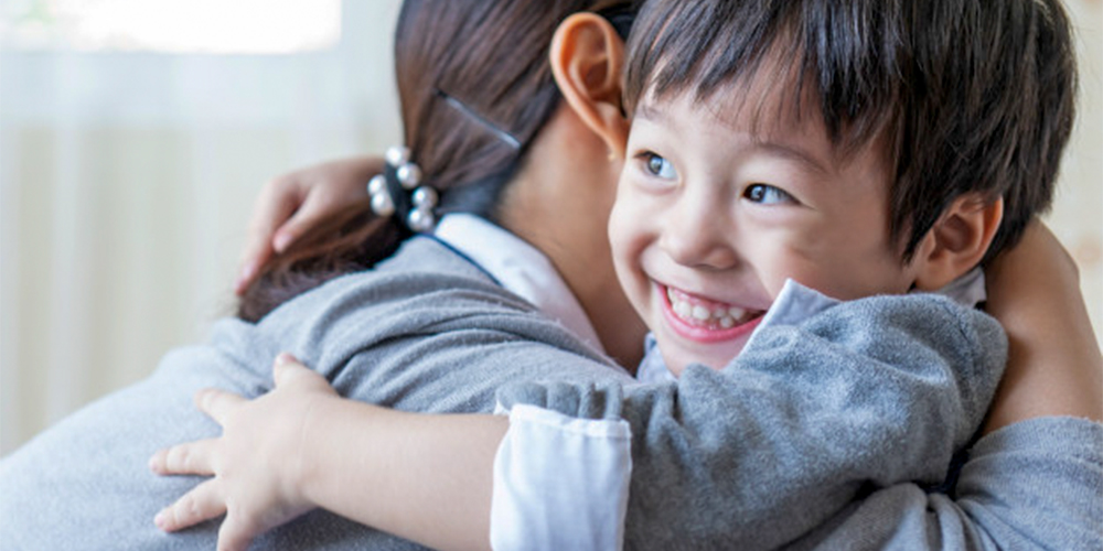 Child beams as his mother hugs
